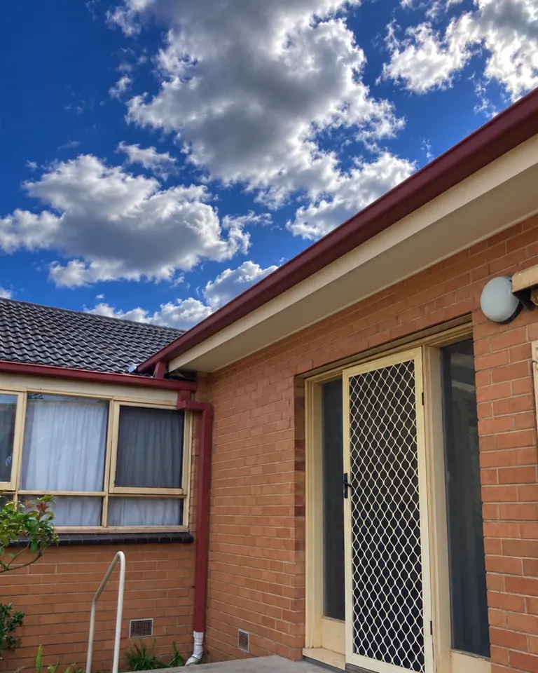 Patio beside a brick home before the pictured roofed structure was added.